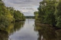 Beautiful view of autumn landscape with forest trees on both sides of navigable river with depth markings.