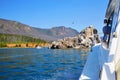 Beautiful view of lake Baikal on a summer day. View from the yacht. A small rocky island where gulls and cormorants nest