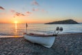 Beautiful view of a boat on a sandy beach with sunset, with an island in the middle of the Mediterranean Sea Royalty Free Stock Photo