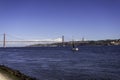 Beautiful view of the Bridge 25th of April over the river Tagus in the heart of Lisbon in Portugal. Small sailing boat and fishing Royalty Free Stock Photo