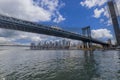 Beautiful view of Brooklyn Bridge over Hudson River and skyscrapers of Manhattan against blue sky with white clouds. Royalty Free Stock Photo