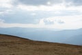 Beautiful view of the carpathian moun landscape with green meadows, trees, dark low clouds on the mountains in the background.