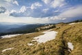 Beautiful view of Carpathian mountains in early spring. Hill with dry grass and spots on snow and fantastic panorama of distant fo Royalty Free Stock Photo