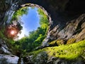Big hole in the ceiling of a cave, blue sky and surrounding vegetation - Portile Bihorului Cave, Apuseni natural park, Romania Royalty Free Stock Photo