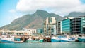 Beautiful view of docked boats on the riverbank with buildings and mountain in the background