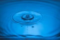 Beautiful view of drops making circles on blue water surface isolated on blue background. Royalty Free Stock Photo