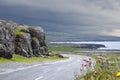 Beautiful view of an empty road near the Irish ocean coast under a gloomy sky