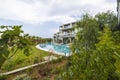 Beautiful view of exterior of hotel building with swimming pool through green trees. Greece.
