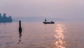 Beautiful view of a fishing boat on a lake, pine trees on the sunset sky background Royalty Free Stock Photo