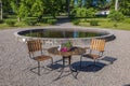 Beautiful view of flowers on outdoor table with two chairs near water pond. Royalty Free Stock Photo