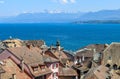 Beautiful view at Geneva lake and french Alps mountains with snow tops through roofs of old town of Nyon Royalty Free Stock Photo