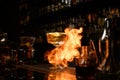 Beautiful view of glass with cocktail on fire stands at bar counter.