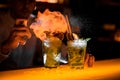 beautiful view on glasses with iced mojito cocktail on which hand of bartender splashes and sets fire