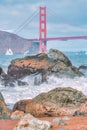 Beautiful view of the Golden Gate Bridge in San Francisco against the background of rocky cliffs and waves of the Pacific Ocean.