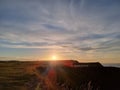 Beautiful view of the green fields and cloudy sky with the shining sun at sunset. Royalty Free Stock Photo