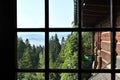 Beautiful view on green forest, blue sky and mountains through a wooden window frame of an old house cottage on a slope of a hill Royalty Free Stock Photo