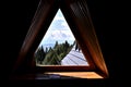 Beautiful view on green forest, blue sky and mountains through a wooden window frame of an old house cottage on a slope of a hill Royalty Free Stock Photo