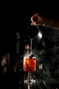 Beautiful view on hand of girl bartender accurate pours steaming liquid from steel mixing cup into drinking glass