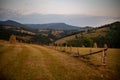 Beautiful view of hay stacks on the brown fields with a wooden fence under sunset sky Royalty Free Stock Photo