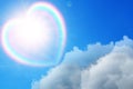 Beautiful view of heart shaped cloud with rainbow in blue sky on sunny day Royalty Free Stock Photo