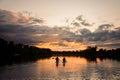 Beautiful view of horizon and sunset and river on which pair of people swim on the sup boards