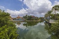 Beautiful view of hotel building with swimming pool and blue water surface of pond with blue sky reflection with white clouds. Royalty Free Stock Photo