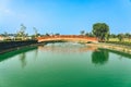 Beautiful view of Japanese style red wooden bridge over emerald pond with fountains against nature of paddy field outdoors. Royalty Free Stock Photo