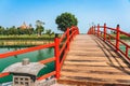 Beautiful view of Japanese style red wooden bridge over emerald pond with fountains against nature of paddy field outdoors. Royalty Free Stock Photo