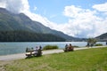 Beautiful view of the lake of St. Moritz and people resting on the benches.