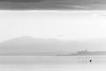 Beautiful view of Trasimeno lake Umbria, Italy at sunset, with a man on a canoe and Castiglione del Lago town on the Royalty Free Stock Photo