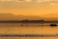 Beautiful view of Trasimeno lake Umbria, Italy at sunset, with orange tones, birds on water, a man on a canoe and Royalty Free Stock Photo