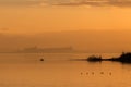 Beautiful view of Trasimeno lake Umbria, Italy at sunset, with orange tones, birds on water, a man on a canoe and Royalty Free Stock Photo