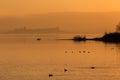 Beautiful view of Trasimeno lake Umbria, Italy at sunset, with orange tones, birds on water, a man on a canoe and Royalty Free Stock Photo