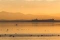 Beautiful view of Trasimeno lake Umbria, Italy at sunset, with orange tones, birds on water, a man on a canoe and Royalty Free Stock Photo