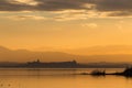 Beautiful view of Trasimeno lake Umbria, Italy at sunset, with orange tones, birds on water, a man on a canoe and Royalty Free Stock Photo