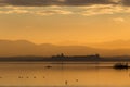 Beautiful view of Trasimeno lake Umbria, Italy at sunset, with orange tones, birds on water, a man on a canoe and Royalty Free Stock Photo