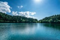 Beautiful view of a lake with white pluffy cloudy sky and mountain background. Travel Tourism concept.