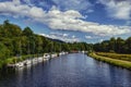 Beautiful view of line of boats anchored on the riverbank in Loch Ness and surrounded by trees