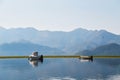 A beautiful view at lonely boats in the middle of the lake Skadar with blue mountain view at background in Montenegro National