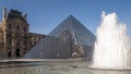 Beautiful view of the Louvre pyramid with fountain and water jets in action, Paris, France