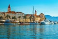 Anchored boats and waterfront promenade with palms in Trogir, Croatia