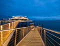 Beautiful view of a modern metallic pier covered in bright lights gleaming under the night sky Royalty Free Stock Photo