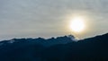 Beautiful view on the mountains from the top through the clouds. Jagged blue silhouettes mountain range.