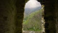 Beautiful view of mountains from window of ruins. Action. Stone arch from ruins with view of green mountains. Green