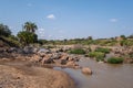 Beautiful view of a muddy river surrounded by rocks and trees under the blue sky in Samburu, Kenya Royalty Free Stock Photo