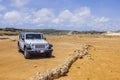 Beautiful view of off-road truck on yellow desert landscape and pale blue sky with white clouds on background. Royalty Free Stock Photo