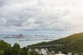 Beautiful view of oil tank near mountain and port ship yard and bridge with working crane for import export in sea under dusk