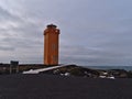 Orange colored SvÃÂ¶rtuloft lighthouse on the rough northwestern coast of Snaefellsnes in winter with path and information sign.