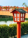 Beautiful view of outdoor lamps on walkway for garden lighting in summer park with blurred image of red bridge in background. Royalty Free Stock Photo