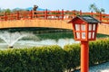 Beautiful view of outdoor lamps on walkway for garden lighting in summer park with blurred image of red bridge in background. Royalty Free Stock Photo